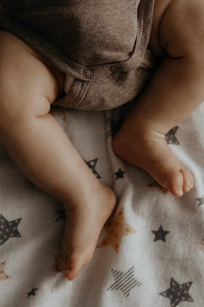 Jambes de bébé allongé sur un lit | Babykare.fr