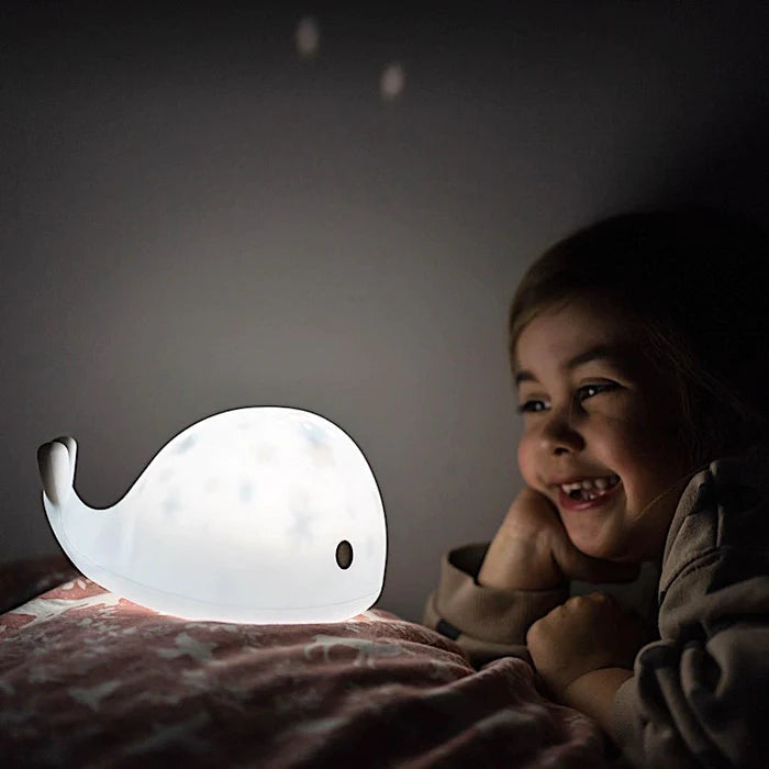 Petite fille admirant une lampe allumée en forme de baleine | Babykare.fr
