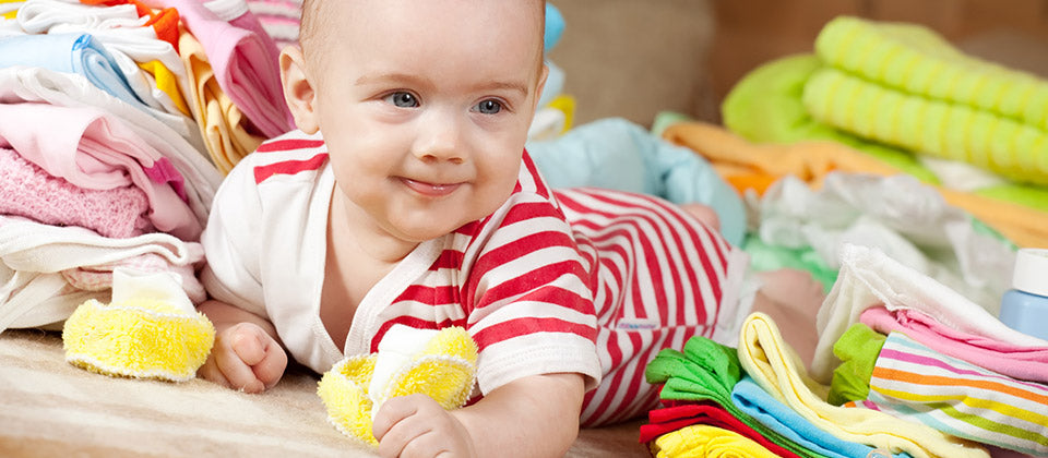 Image d'un bébé entouré de ses vêtements qu'il met au quotidien 