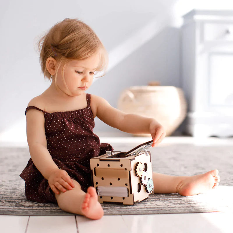 Petite fille jouant avec un cube d'activité en bois | Reggio Montessori