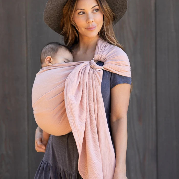 Jeune maman portant son enfant avec une écharpe de portage 